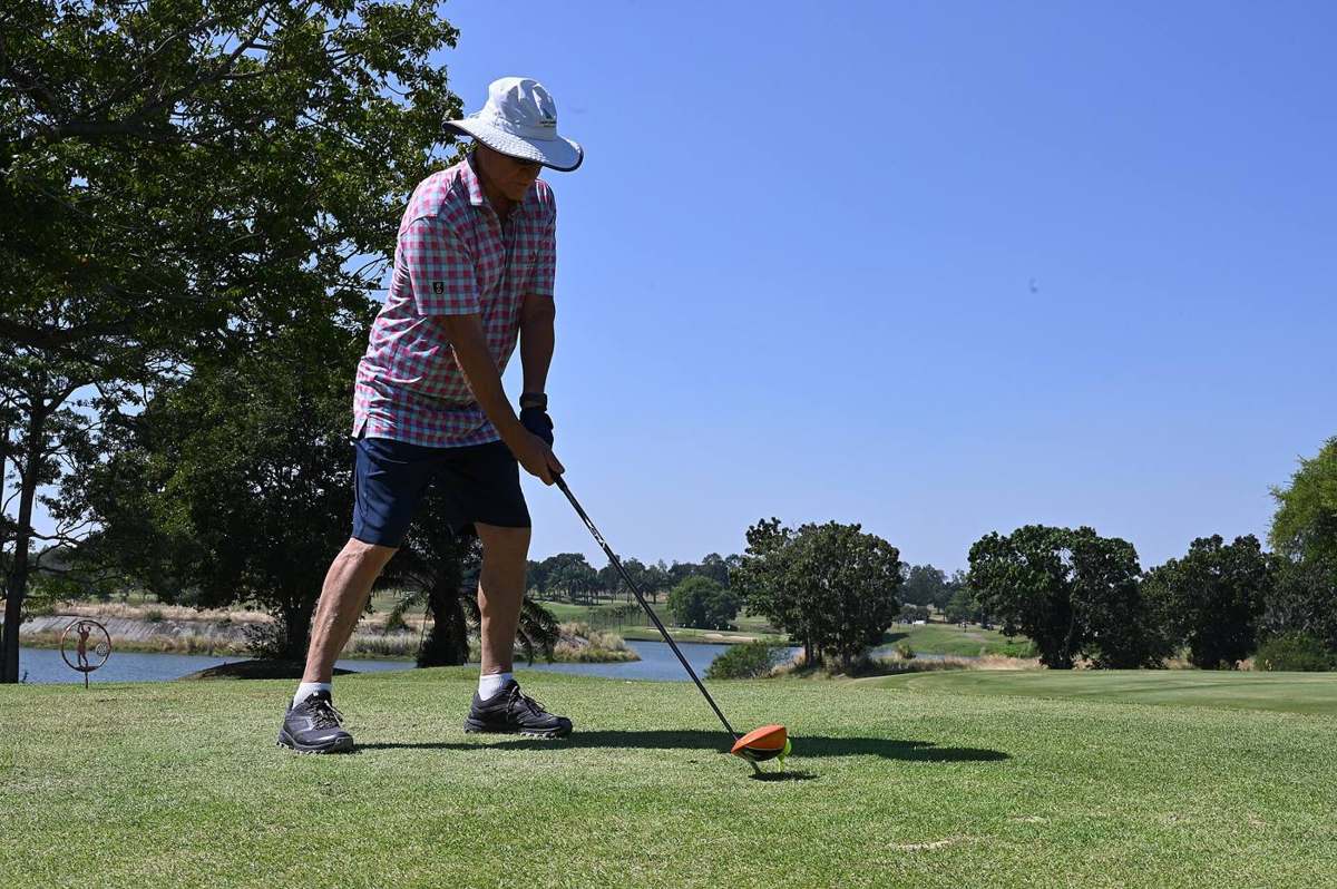 A golfer hitting a tee shot with a driver on a sunny day
